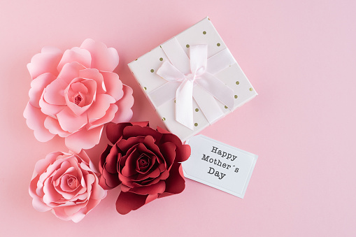 Paper roses with HAPPY MOTHER DAY card and gift box with ribbon on pink background. Copy space. Greeting card.