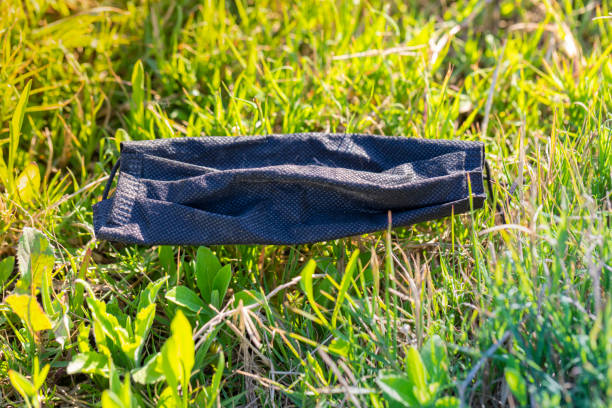 Protective face mask in the river side, new garbage from humans. On the grass...