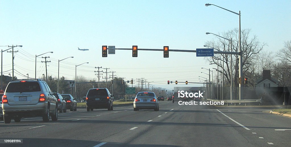 Suburban Traffic Light suburban traffic approaching a stop light with a plane off in the distance. Road Intersection Stock Photo