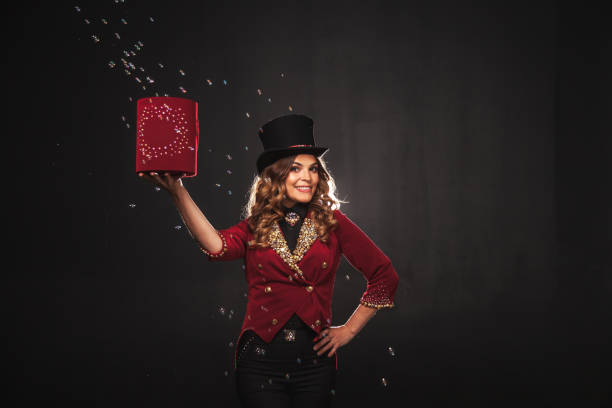 Female magician makes with soap bubbles show, an illusionist in theatrical clothes, on black background. Woman actress in stage costume. Concept of theatrical performance and fun show. Copy space