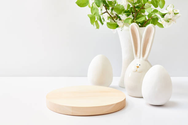 istock Empty round wooden podium for product presentation. Spring flowers in a vase, easter eggs on a light background. Mock up for displaying works 1390894377