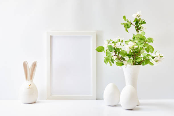 istock Home interior with easter decor. Mockup with a white frame and spring flowers in a vase on a light background 1390894378
