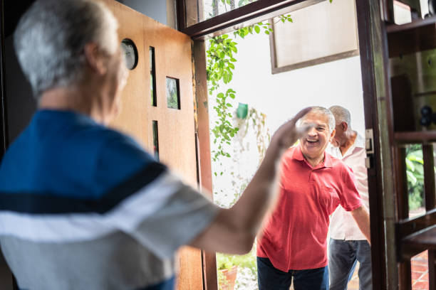 istock Senior man welcoming friends at home 1390895652