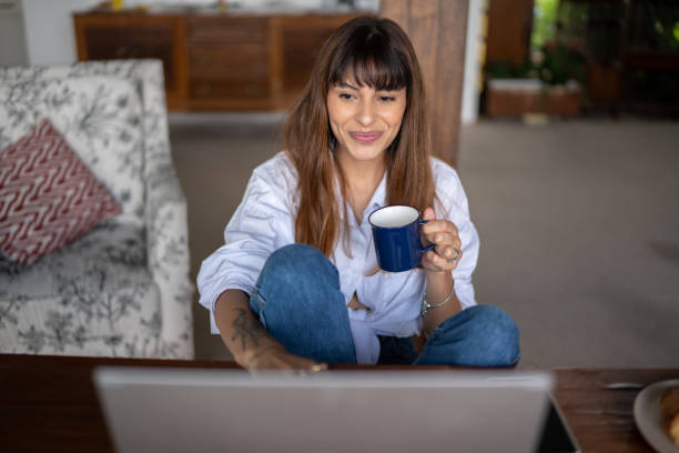 istock Young woman using the laptop and drinking coffee at home 1390895680