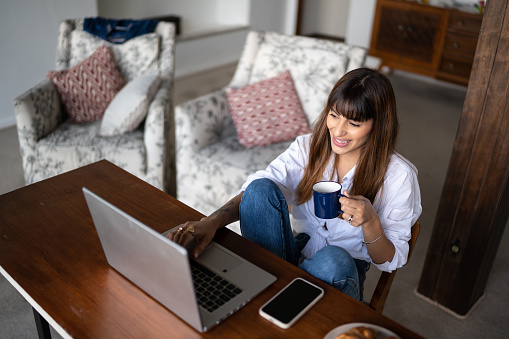 Young woman using the laptop and drinking coffee at home