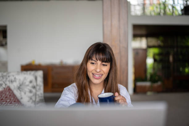 istock Young woman using the laptop and drinking coffee at home 1390895707