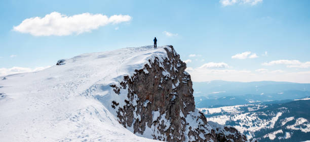Man staying on the peak of a mountain, resting and enjoying the beauty of the spring Carpathians at hiking, Romania