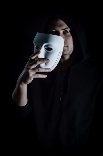 Take off the mask - Portrait of a young hooded man who takes off his mask, letting his gaze be seen, concept for being true and authentic