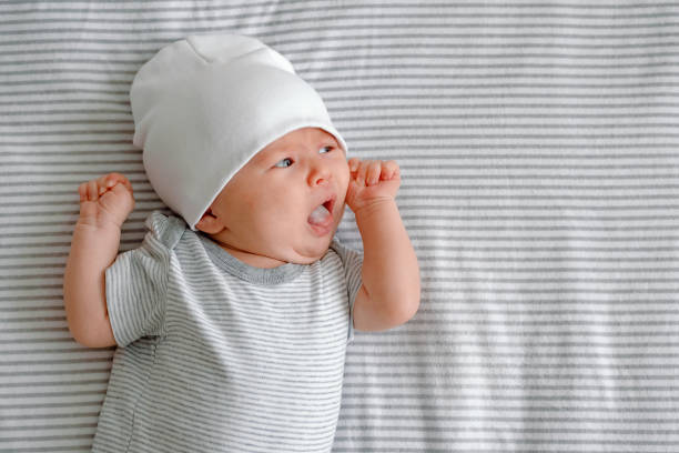 空腹の新生児。縞模様のおむつの上に横たわり、舌を出してミルクを求める赤ん坊。ベビーケア。 - sticking out tongue ストックフォトと画像