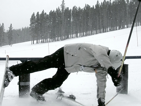 A skier about to hit the ground, after falling off a rail.