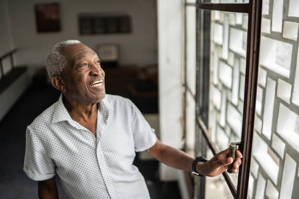 istock Contemplative senior man looking through the window at home 1390898645