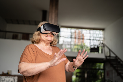 Senior woman using a virtual reality glasses at home