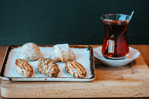 assorted or mixed cookies, mini macaroon and colored macarons, black tea (Turkish tea), cookies and tea served on the wooden table, mini acibadem cookie, salty and sugar cookies