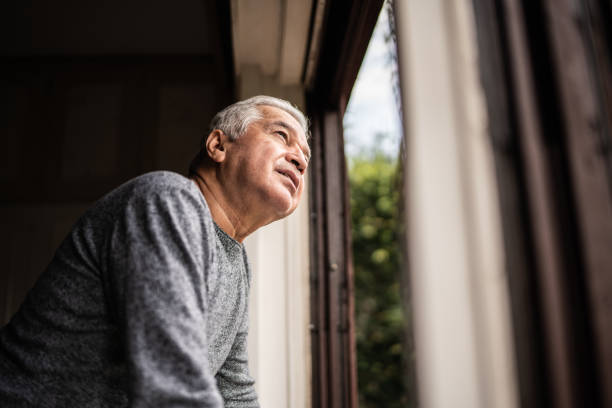 istock Senior man contemplating looking through the window 1390899613