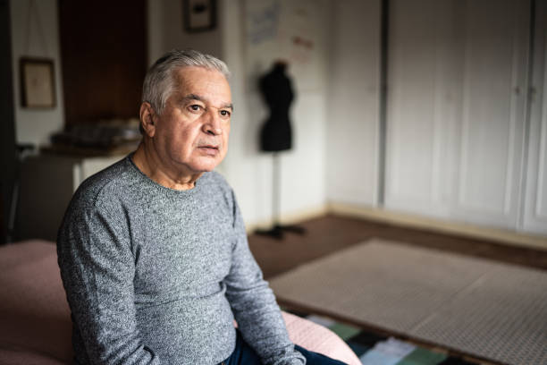 senior man sitting on the bed and looking away - 65 69 jaar fotos stockfoto's en -beelden
