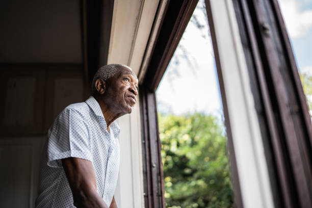 Senior man contemplating looking through the window