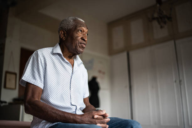 homme âgé assis sur le lit et détournant le regard - tired men african descent sadness photos et images de collection