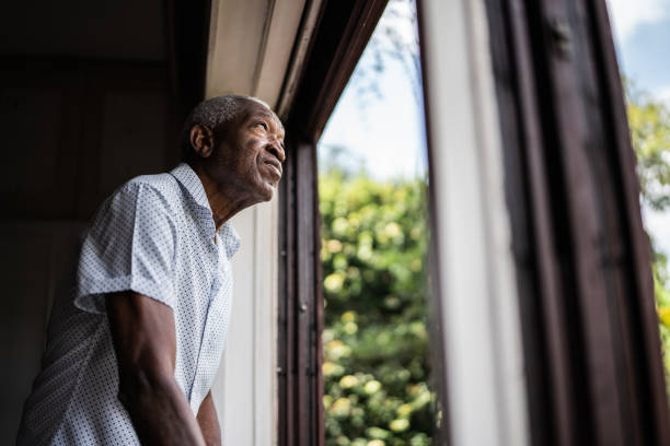 istock Senior man contemplating looking through the window 1390899632