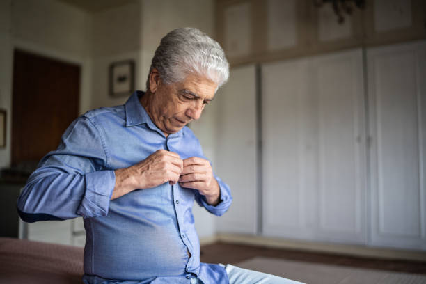 Senior man dressing a shirt at home