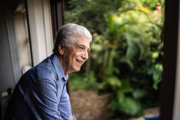 istock Happy senior man contemplating looking through the window 1390899663