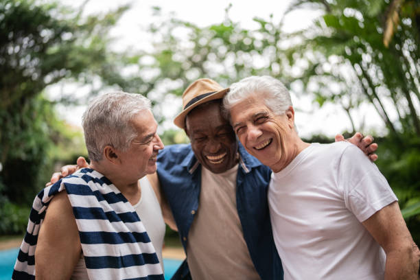 hommes âgés s’embrassant lors d’une fête à la piscine - active seniors retirement enjoyment swimming pool photos et images de collection
