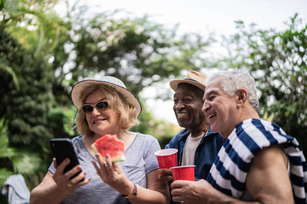 istock Senior friends taking selfies using mobile phone on a pool party 1390900032