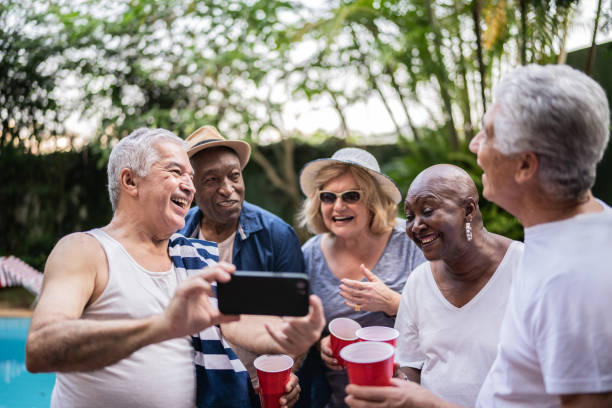 istock Senior friends having fun and using mobile phone on a pool party 1390900062