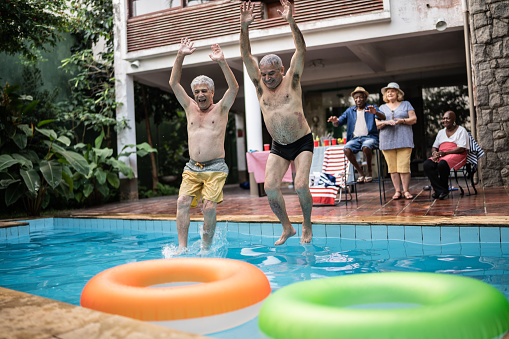 Senior men jumping in the swimming pool