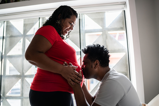 Man kissing woman's pregnant stomach