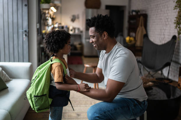 istock Father helping son with backpack at home before leaving to school 1390901271