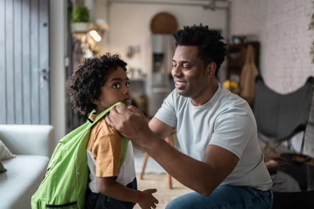 istock Father helping son with backpack at home before leaving to school 1390901291