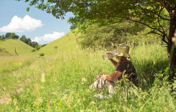 Mature woman drinking water under tree in nature