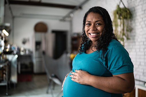 Portrait of a pregnant woman touching her belly at home