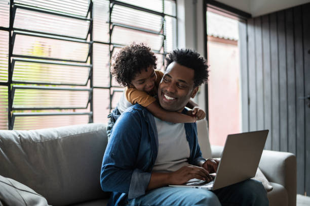 istock Father using the laptop while son is on his back at home 1390901655