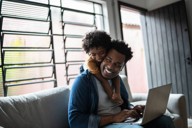 istock Father using the laptop while son is on his back at home 1390901665