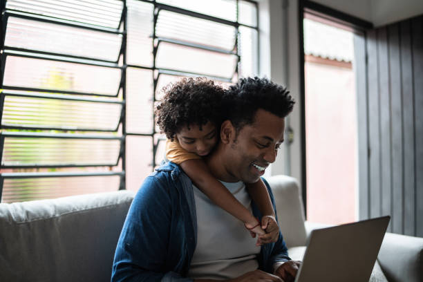istock Father using the laptop while son is on his back at home 1390901680