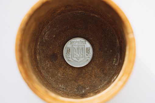 Ukrainian coin at the bottom of a wooden box in a piggy bank on a white background