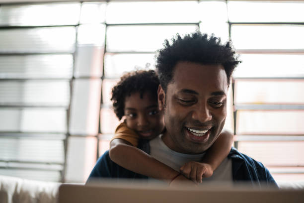 istock Father using the laptop while son is on his back at home 1390901724