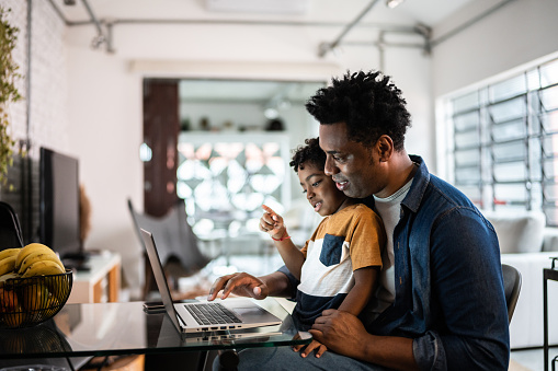 Father using the laptop with son at home