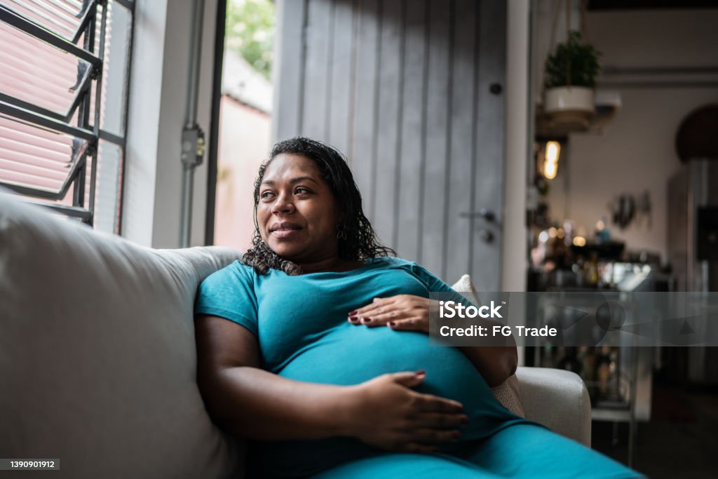 Pregnant woman touching her belly and contemplating at home Pregnant Stock Photo