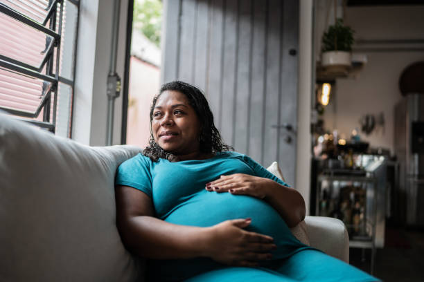 pregnant woman touching her belly and contemplating at home - hamile stok fotoğraflar ve resimler