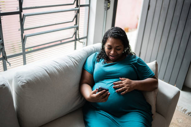 istock Pregnant woman doing a video call using mobile phone at home 1390901916