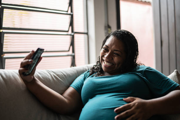 istock Pregnant woman doing a video call using mobile phone at home 1390901931