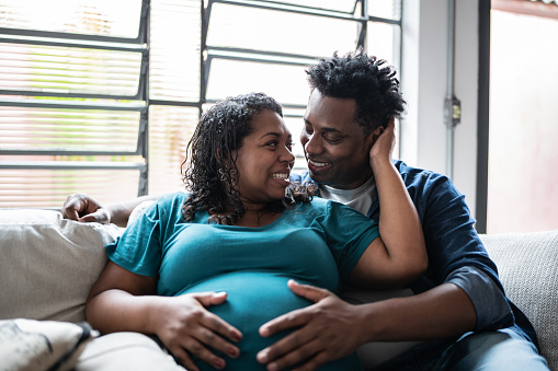 Couple touching her pregnant belly at home