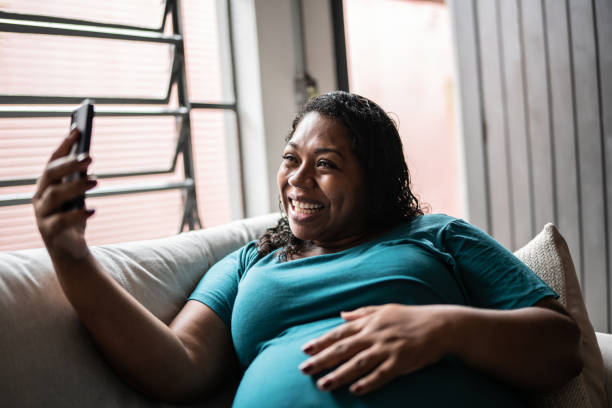 Pregnant woman doing a video call using mobile phone at home