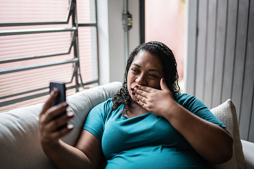 Pregnant woman doing a video call using mobile phone at home