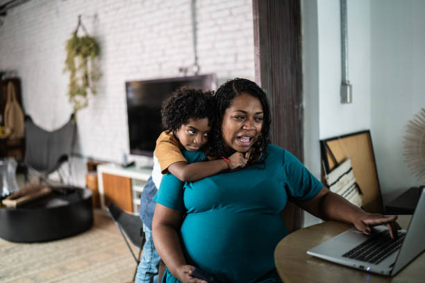 istock Pregnant woman using laptop at home with son 1390902201