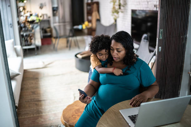 istock Pregnant woman using laptop at home with son 1390902204