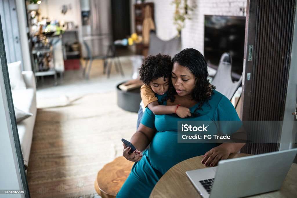 Pregnant woman using laptop at home with son Pregnant Stock Photo
