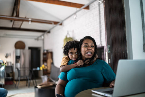istock Pregnant woman using laptop at home with son 1390902206